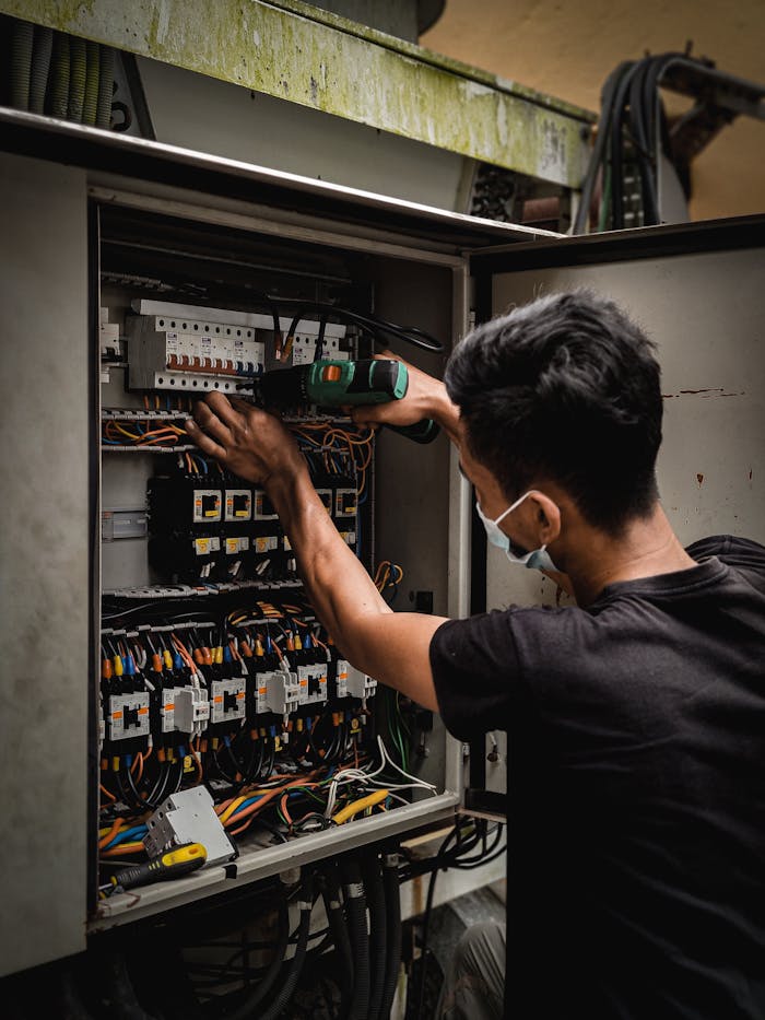 gallery-04 Technician working on circuit breaker panel, adjusting electrical wires indoors.